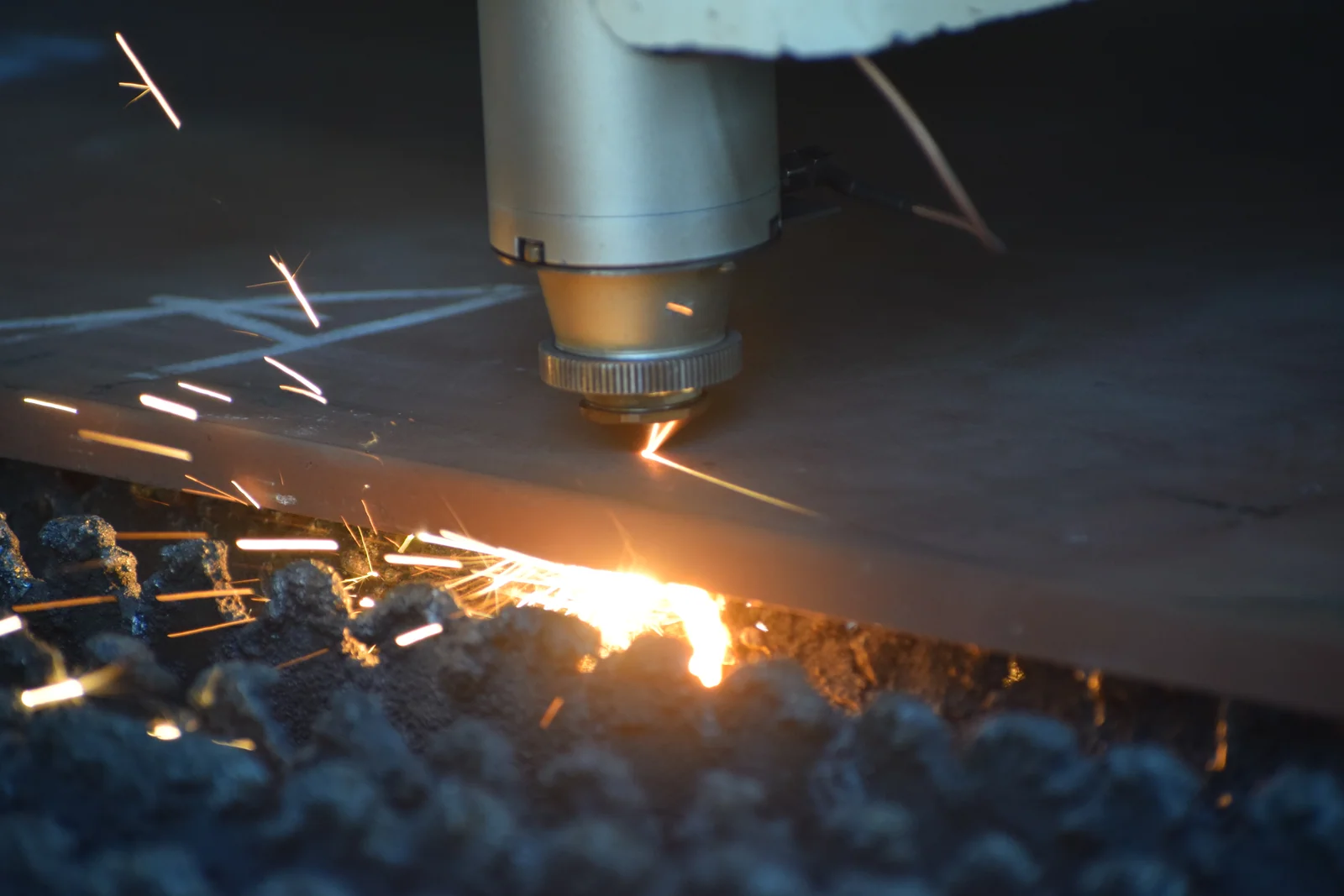 Laser cutting head cutting a steel sheet with a shower of sparks at Jhandeana Industries